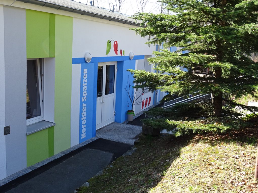 Kindergartengebäude Herolder Spatzen mit grüner und blauer Farbe auf weißem Grund farbig hervorgehoben